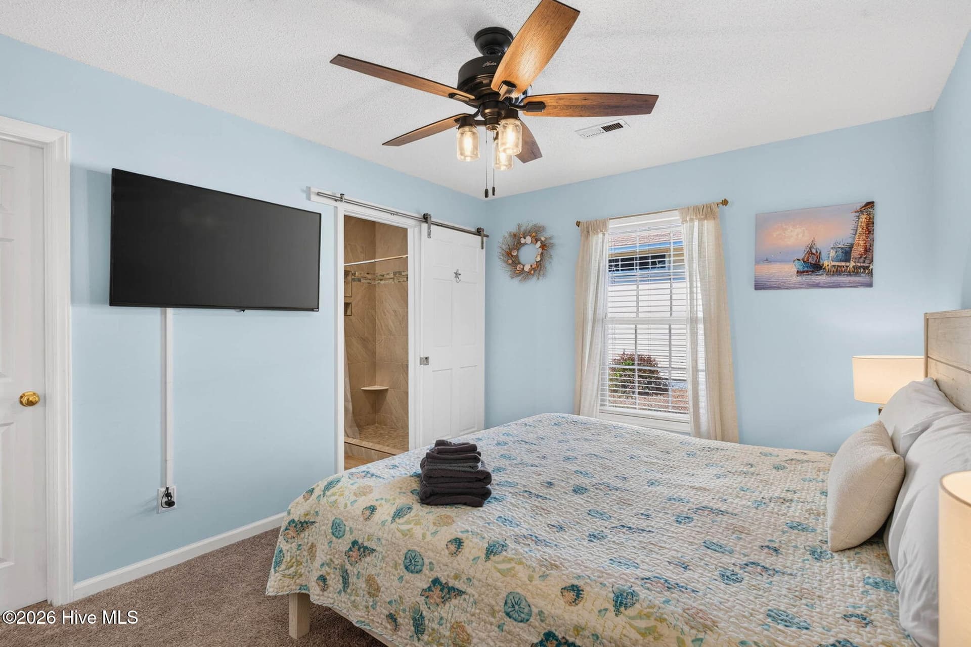 Comfortable primary bedroom with ceiling fan, natural light, and convenient access to a private ensuite bath. - 1650 Frink Street SW, Ocean Isle Beach, NC 28469