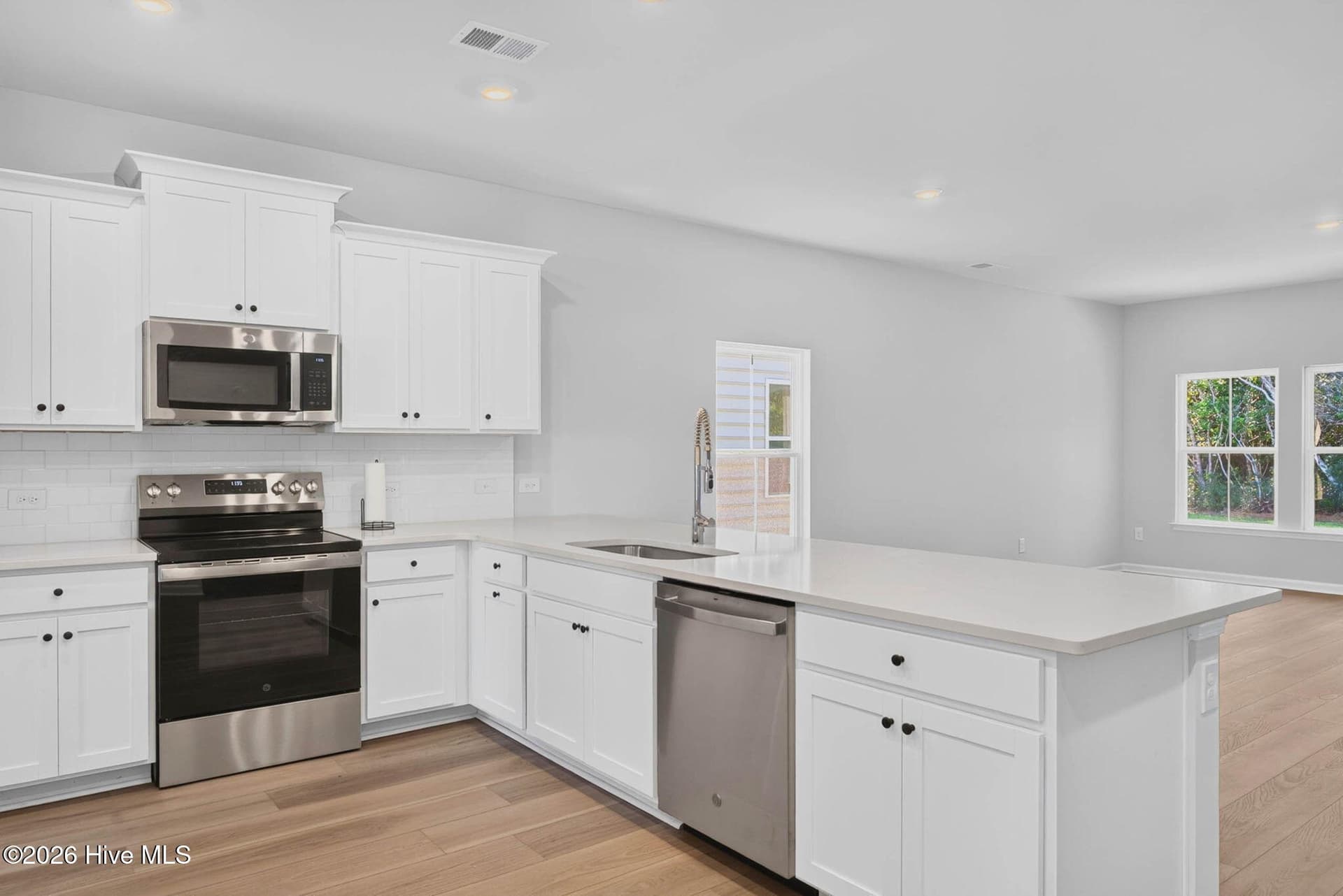 Open-concept kitchen with a spacious center island, stainless steel appliances, and abundant cabinetry. - 3447 Sandhill Crane Drive SW, Ocean Isle Beach, NC 28469