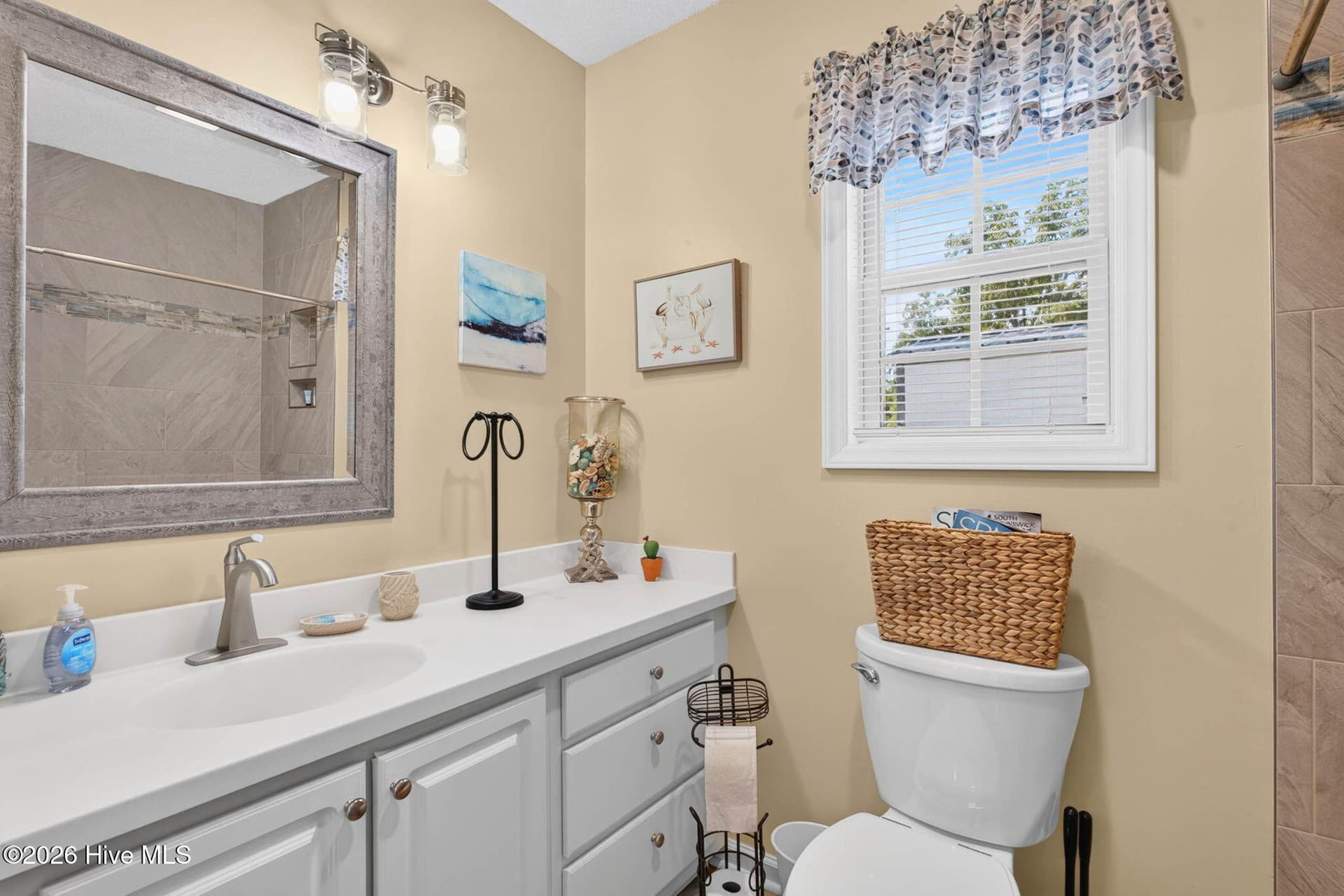 Private primary bathroom with a spacious vanity, natural light, and custom tiled walk-in shower. - 1650 Frink Street SW, Ocean Isle Beach, NC 28469