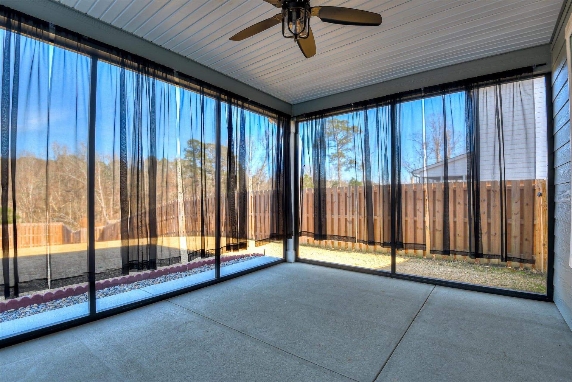 Enjoy an unobstructed, beautiful view of the green space from this upgraded, screened-in covered patio with Clear VIEW Mesh Custom-added by the owners, this premium outdoor living space offers high-end luxury and incredible added value to this move-in-ready home. (Removable drapes are featured in Picture) - 903 Lillian Park Drive, Grovetown, GA 30813