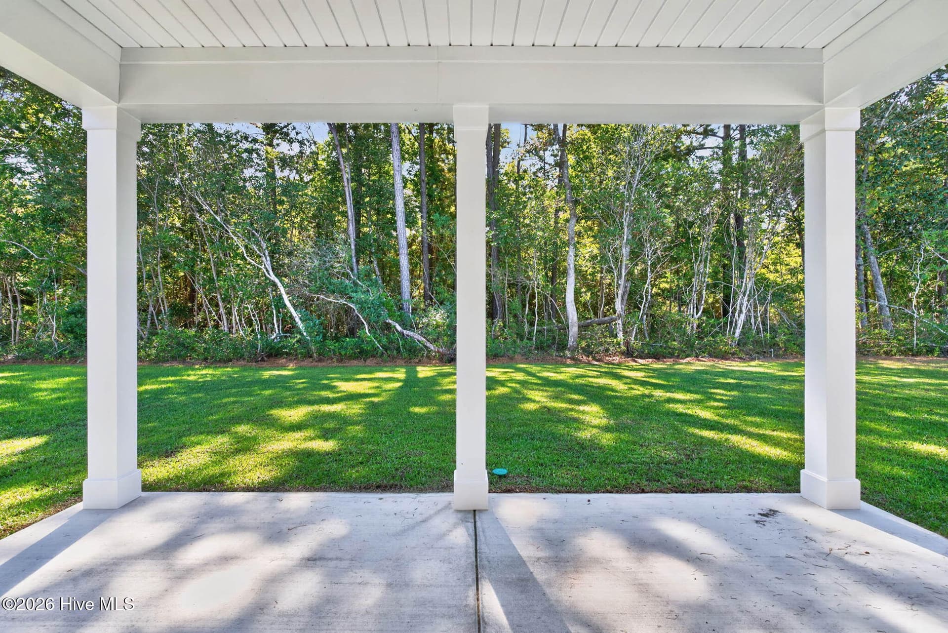 Spacious covered patio with a wooded backdrop, ideal for relaxing or entertaining outdoors. - 3447 Sandhill Crane Drive SW, Ocean Isle Beach, NC 28469