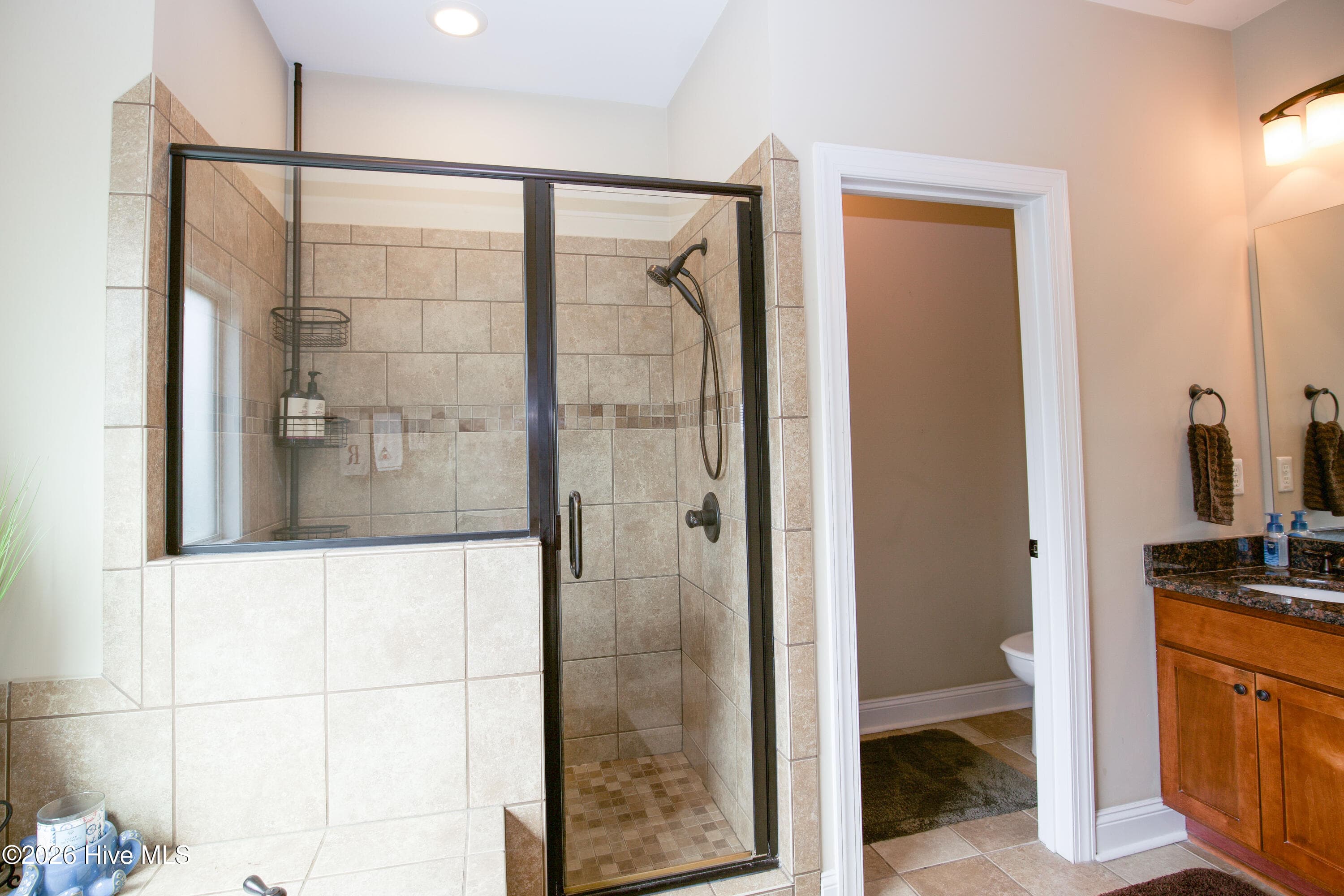 Glass-enclosed tiled walk-in shower in the primary bath. - 899 Seagull Drive, Vass, NC 28394, Vass