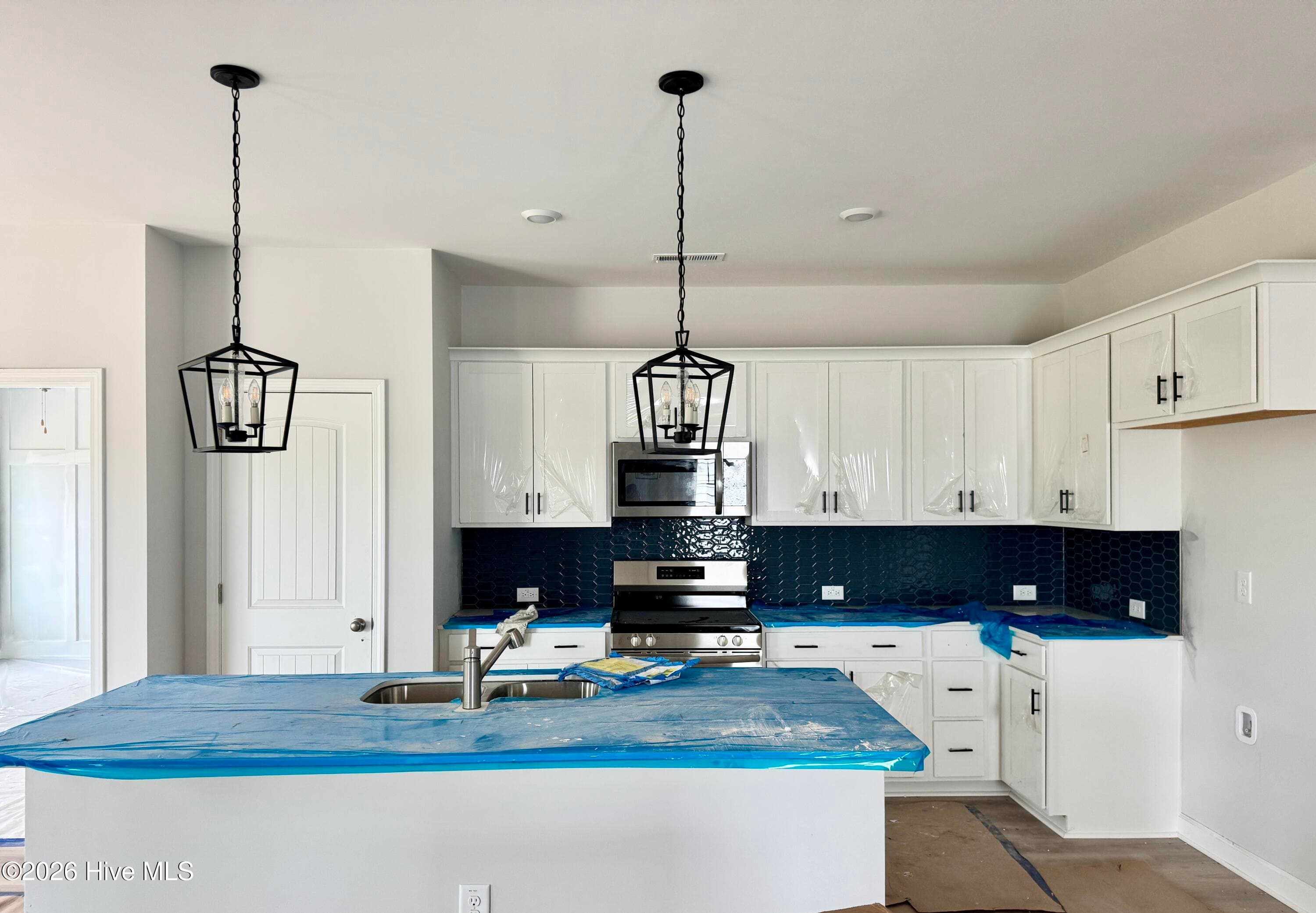 Kitchen features abundant cabinetry, quartz counterspace, tile backsplash, and stainless appliances. - 4188 Workman Loop 89, Leland, NC 28451
