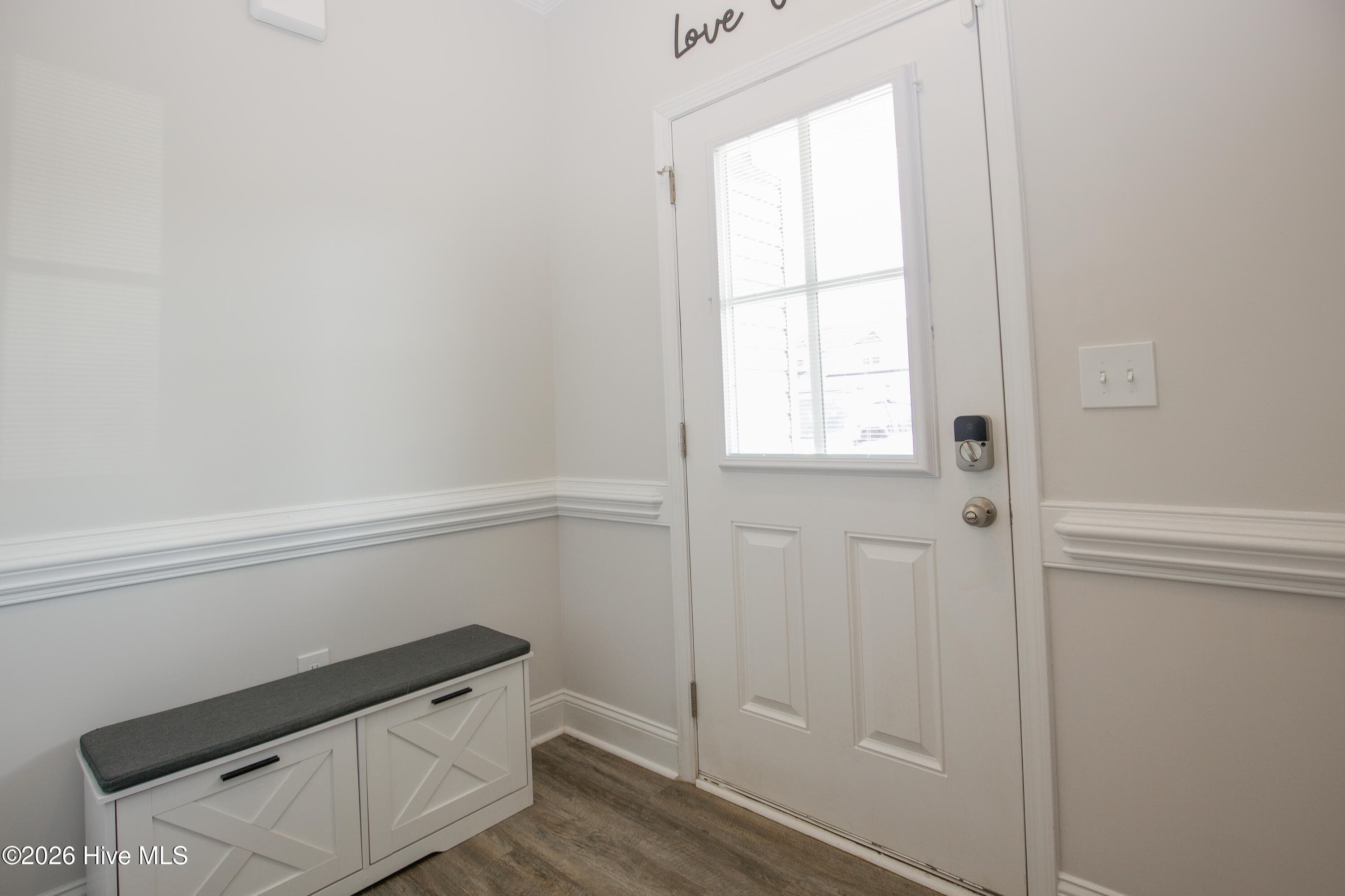 Just inside the front door, the foyer features chair-rail trim and wood-look flooring that continues into the main living areas. The space gives you room to set down keys and shoes before stepping into the rest of the house. The front flex room opens just off this entry, so a home office or sitting room stays separate from the main gathering spaces. - 221 Vega Lane, Linden, NC 28356