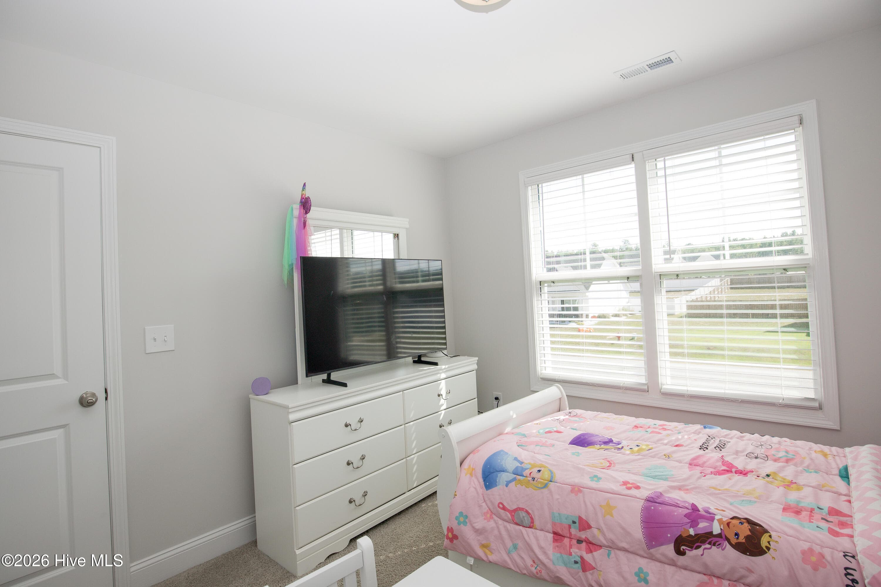 From this corner, the third bedroom shows how a dresser, bed, and other furniture can fit together without crowding the room. The double window and the entry door are on adjacent walls, leaving a long wall free for furniture. According to the floor plan, the room measures approximately 11 feet by 11'6". - 221 Vega Lane, Linden, NC 28356
