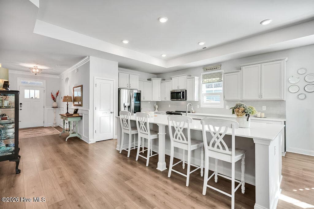 Chef-style kitchen island is the heart of this home and a natural gathering place. The kitchen also features upgraded premium staggered, color glazed cabinetry with dovetails, a single basin stainless sink, fully tiled backsplash throughout, upgraded stainless refrigerator and oven/range, upgraded granite countertops, brushed nickel lighting package, and custom plantation blinds. - 142 Rice Marsh Way, Wilmington, NC 28412