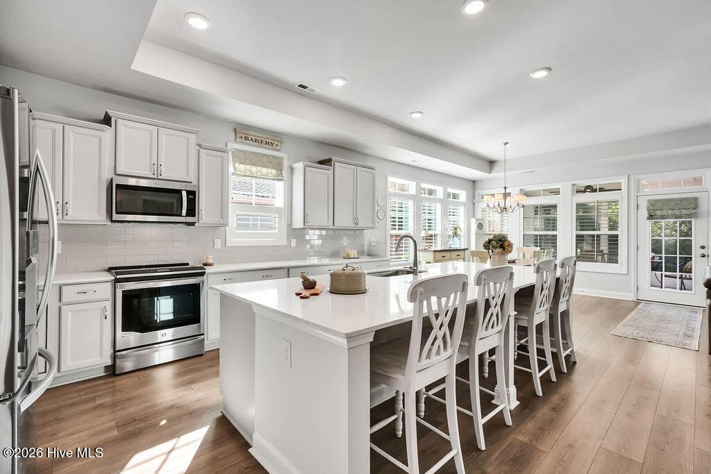 Chef-style kitchen island is the heart of this home and a natural gathering place. The kitchen also features upgraded premium staggered, color glazed cabinetry with dovetails, a single basin stainless sink, fully tiled backsplash throughout, upgraded stainless refrigerator and oven/range, upgraded granite countertops, brushed nickel lighting package, and custom plantation blinds. - 142 Rice Marsh Way, Wilmington, NC 28412