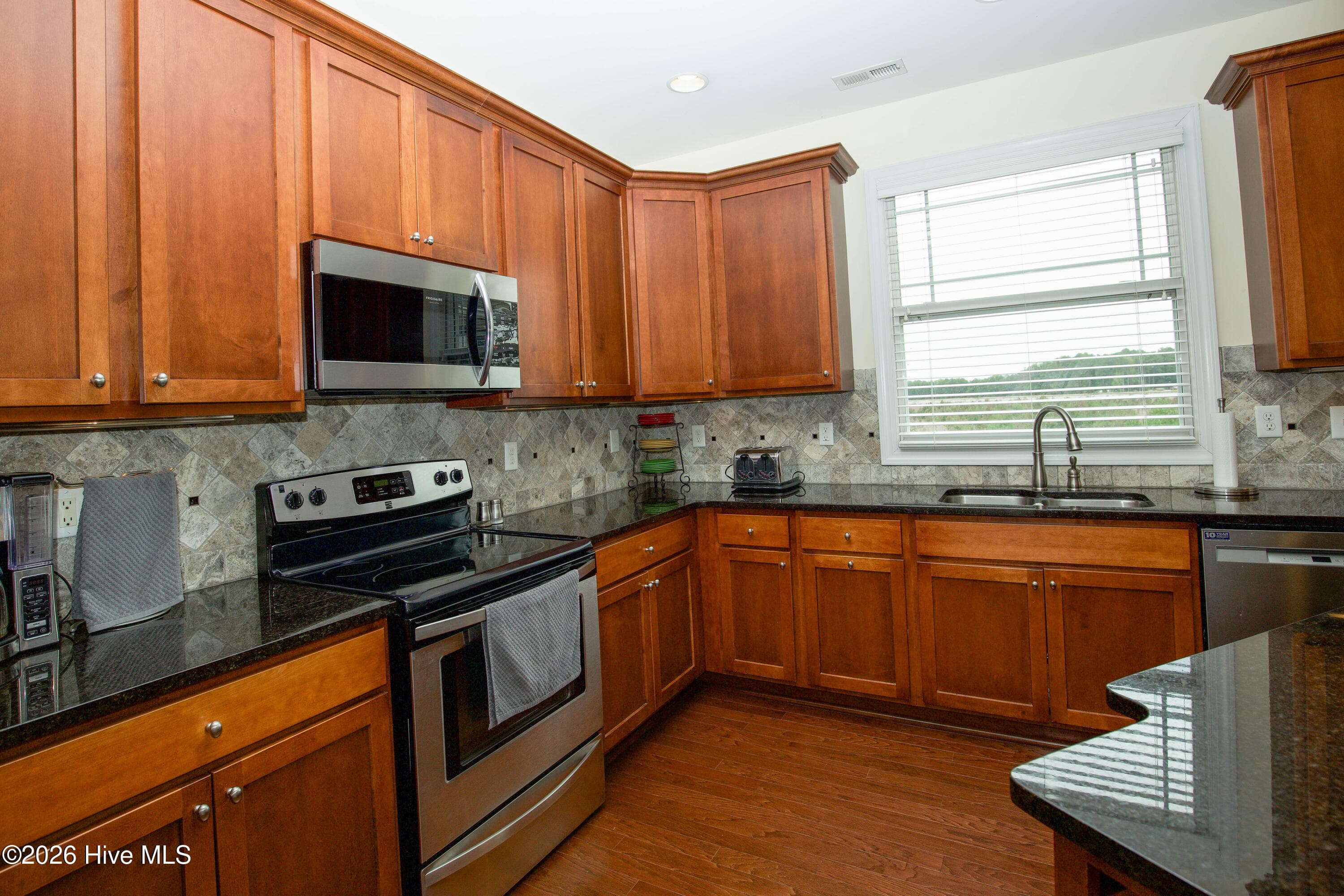 Kitchen sink beneath a window, with cabinetry on three walls. - 899 Seagull Drive, Vass, NC 28394, Vass