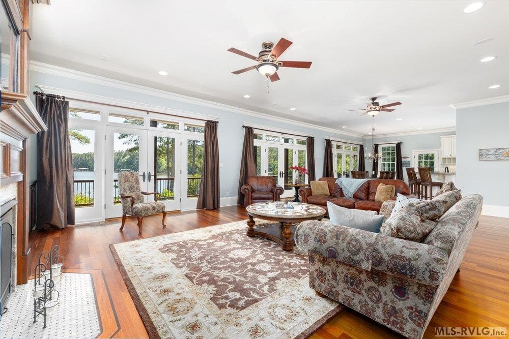 Spacious Traditional Living Room, Comfort while showcasing a beautiful view of Lake Gaston through a wide wall of floor-to-ceiling windows and French Doors. - 381 West Bend Dr., Gasburg VA 23857, Gasburg