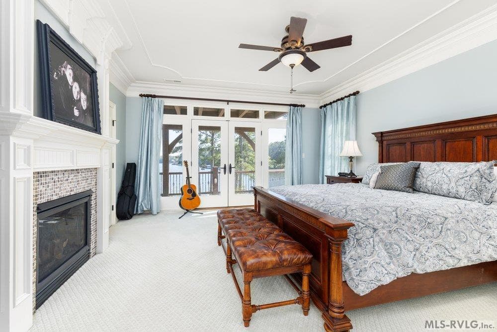 Luxurious Primary Suite, A true sanctuary, featuring a cozy double-sided fireplace and elegant crown molding. French doors open directly to a serene view of Lake Gaston. - 381 West Bend Dr., Gasburg VA 23857, Gasburg