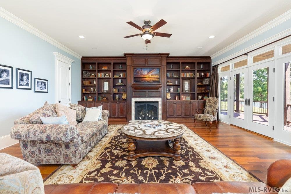 Living Room, The spacious living room is centered around a stunning floor-to-ceiling custom wall unit, featuring wood cabinetry, integrated shelving, and a focal-point fireplace. - 381 West Bend Dr., Gasburg VA 23857, Gasburg