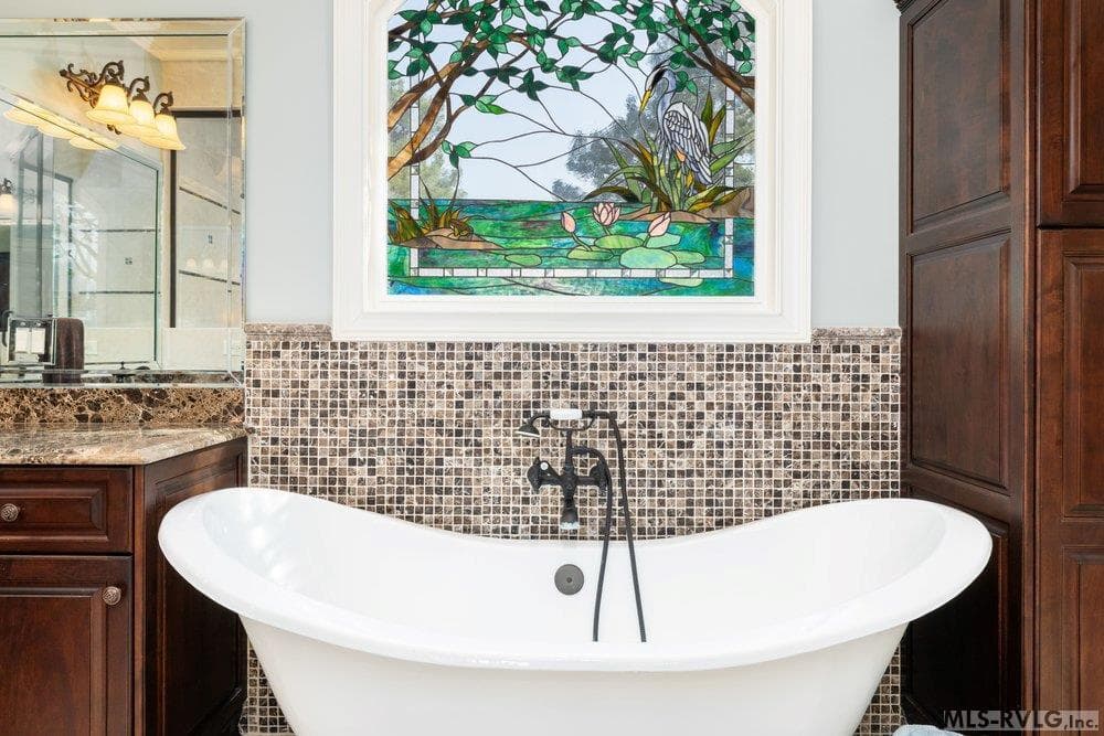 Private Sancturay, Unwind in your freestanding soaking tub, accented by a shimmering mosaic tile backsplash and a vibrant stained glass focal point that brings both artistic flair and natural light. - 381 West Bend Dr., Gasburg VA 23857, Gasburg