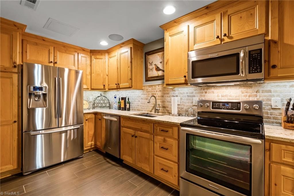 Lower level, fully equipped kitchen with quartz countertops, stainless appliances, tiled backsplash and beautiful cabinetry - 11555 Double Spring Road, Lewisville NC 27023, Lewisville