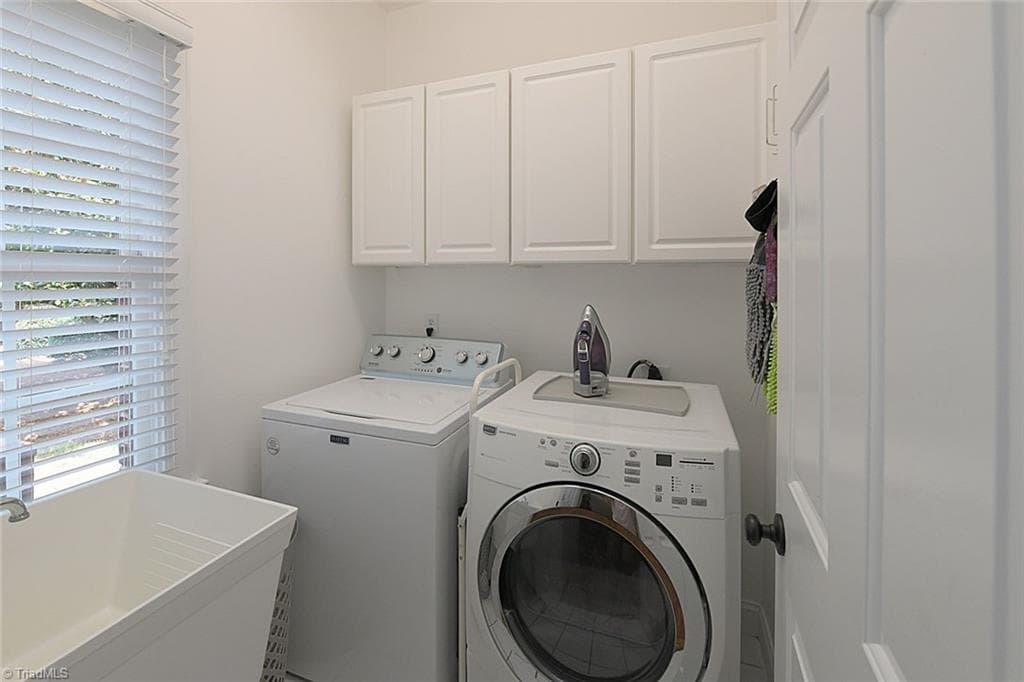 Main-level laundry room featuring a convenient utility sink, additional cabinetry for storage, and a functional layout designed for efficiency. - 1101 Clyde Edgerton Drive, Kernersville NC 27284, Kernersville
