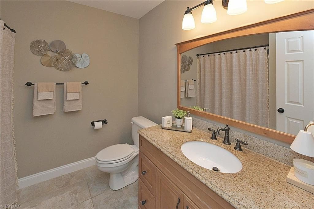 Upper-level bathroom featuring tile flooring, a solid surface vanity, and updated hardware. - 1101 Clyde Edgerton Drive, Kernersville NC 27284, Kernersville