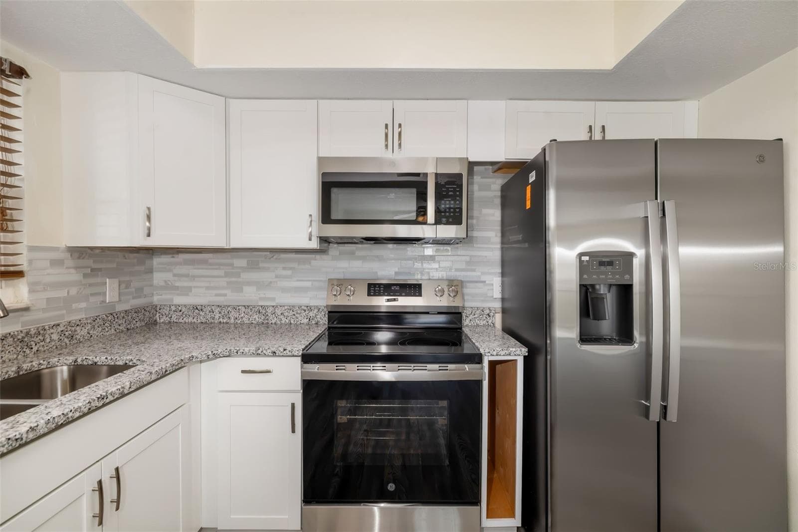 Kitchen – Close (Appliances)Updated kitchen featuring stainless steel appliances, granite countertops, and modern cabinetry.Updated kitchen featuring granite countertops, stainless appliances, and modern cabinetry. - 2513 AVENUE B #B, BRADENTON BEACH