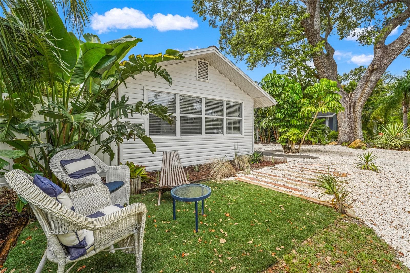 Front Elevation – This charming 1925 bungalow makes a great first impression with tropical landscaping, a wide circular shell drive, and a private seating area nestled under mature palms. - 2705 2ND AVE W, BRADENTON