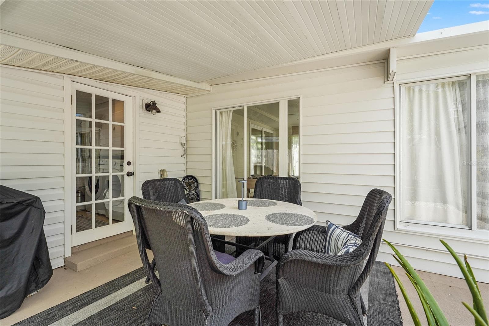 Covered Dining Patio – Dine alfresco under a covered lanai complete with fan, grill station, and cozy all-weather seating—a must-have feature for guests or year-round Florida living. - 2705 2ND AVE W, BRADENTON