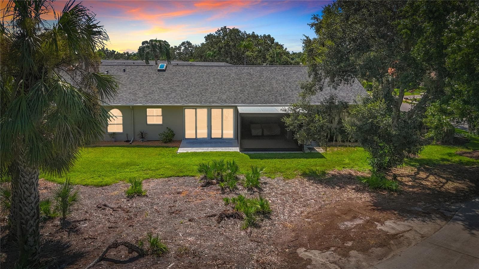 Evening view of villa rear with landscaped green space between villa and golf course - 6948 STONEYWALK CT, BRADENTON