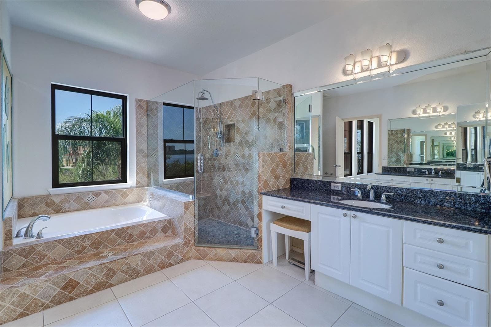 Primary bathroom with updates to garden tub, shower and glass enclosure; separate vanities with granite counter tops and small make up area - 2757 VIA CIPRIANI #1114A, CLEARWATER