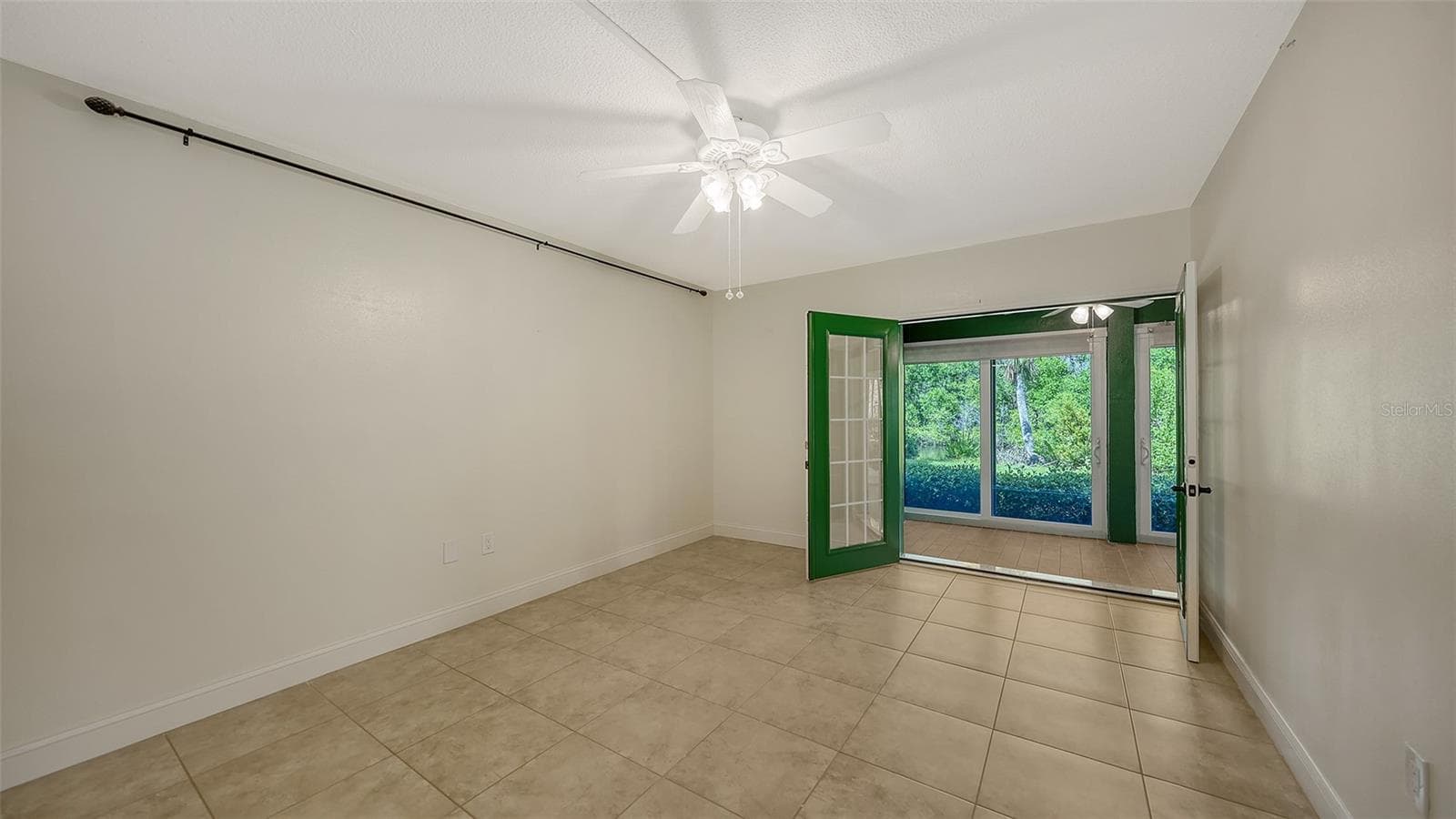 Primary bedroom with French doors leading to private enclosed lanai that runs the length of the unit. - 225 HOURGLASS WAY #103, SARASOTA