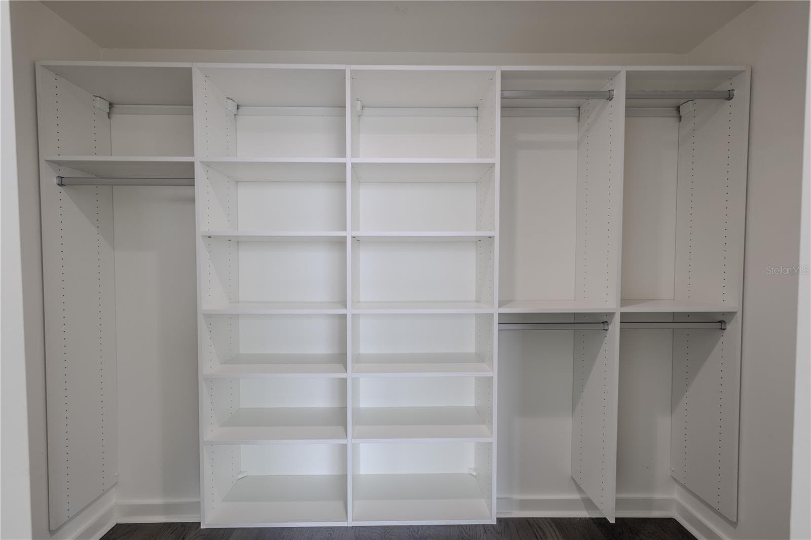 The spacious walk-in closet for Bedroom 2 offers exceptional organization with a custom built-in system featuring multiple open shelves and double hanging sections. Clean white finishes and adjustable shelving provide versatility for clothing, shoes, and accessories, while the streamlined layout maximizes storage and accessibility. Perfectly designed to complement the modern style of the suite, this closet delivers both form and function in a bright, polished space. - 920 N OSCEOLA AVE #703, CLEARWATER