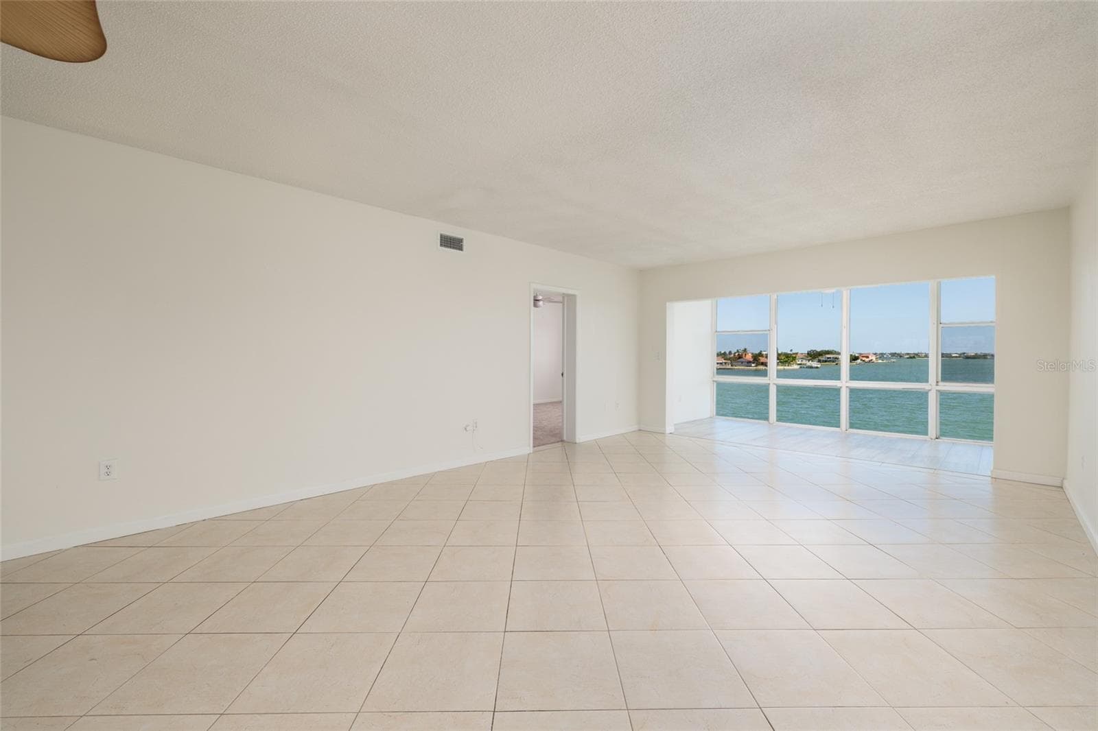 Living area, Florida room & doorway to primary bedroom. Boca Ciega Bay views. - 6061 2ND ST E #55, ST PETE BEACH