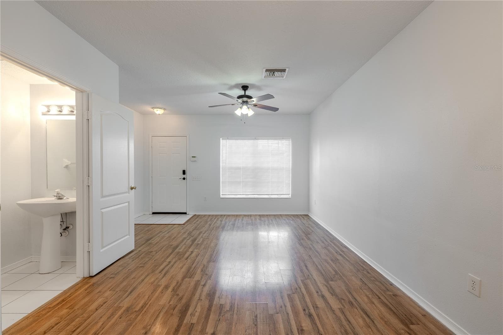 The Living room features neutral tones, wood laminate flooring, a ceiling fan with light kit and picture window. - 2432 LAKE WOODBERRY CIR, BRANDON