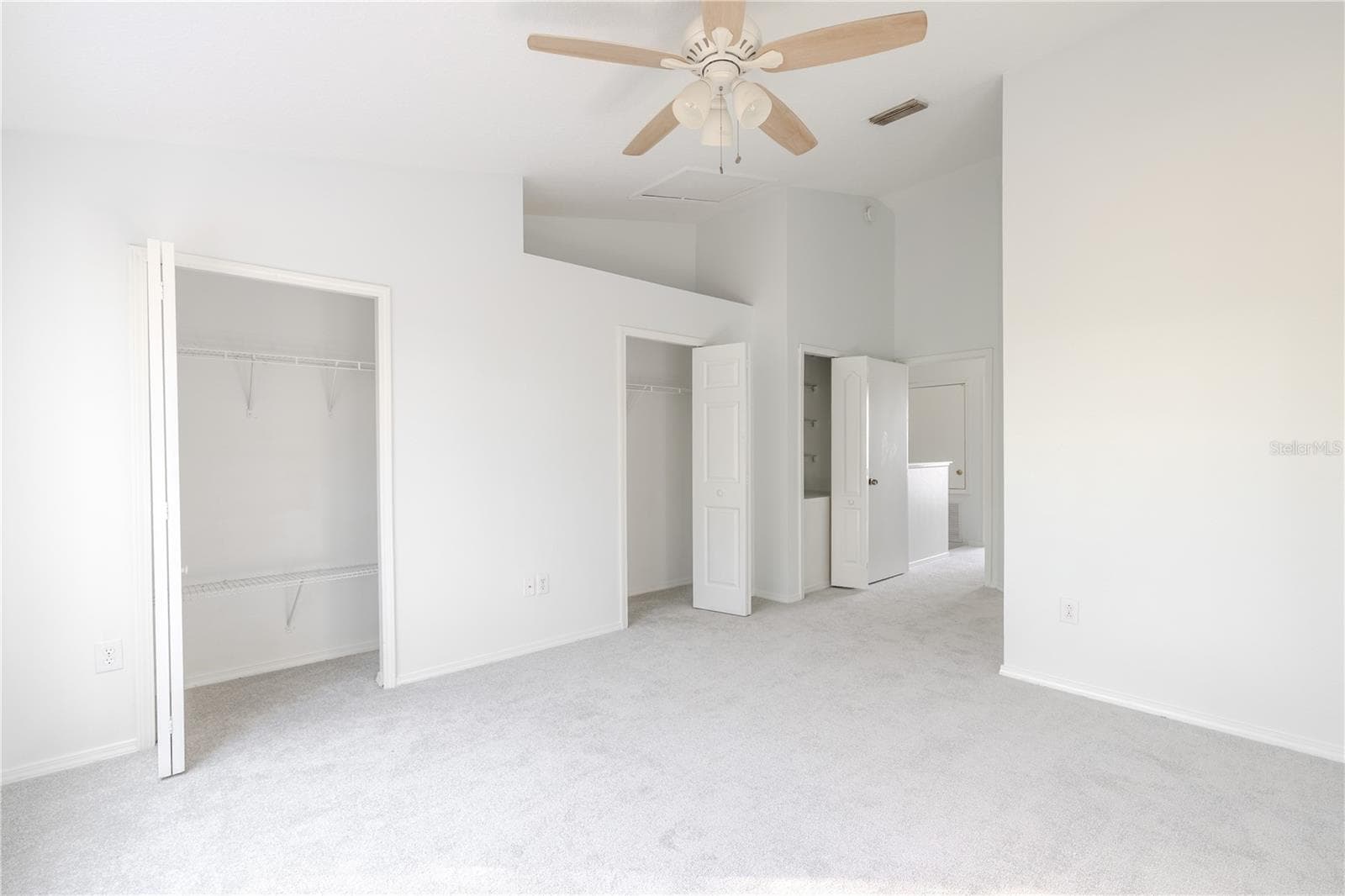 The Primary bedroom features neutral tone walls and carpet, a ceiling fan with light kit and vaulted ceiling. - 2432 LAKE WOODBERRY CIR, BRANDON