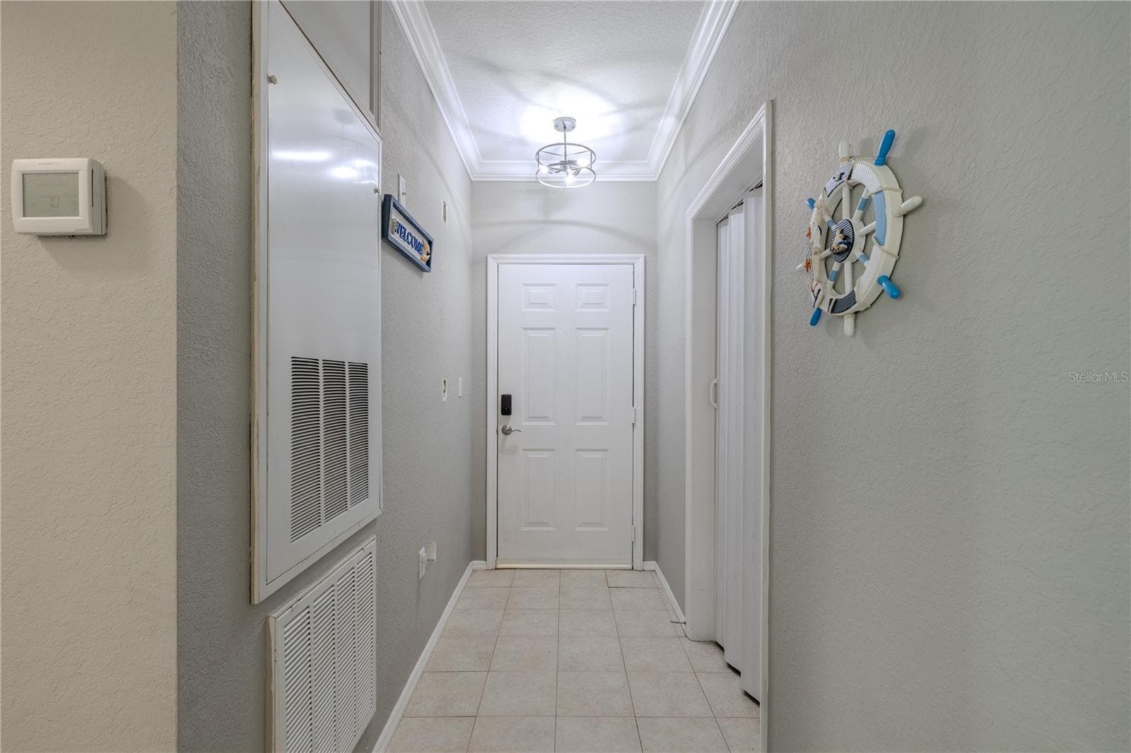 Bright entry foyer with tile flooring and modern lighting, featuring a convenient laundry/utility closet to the left for easy everyday living. - 2738 VIA TIVOLI #220B, CLEARWATER