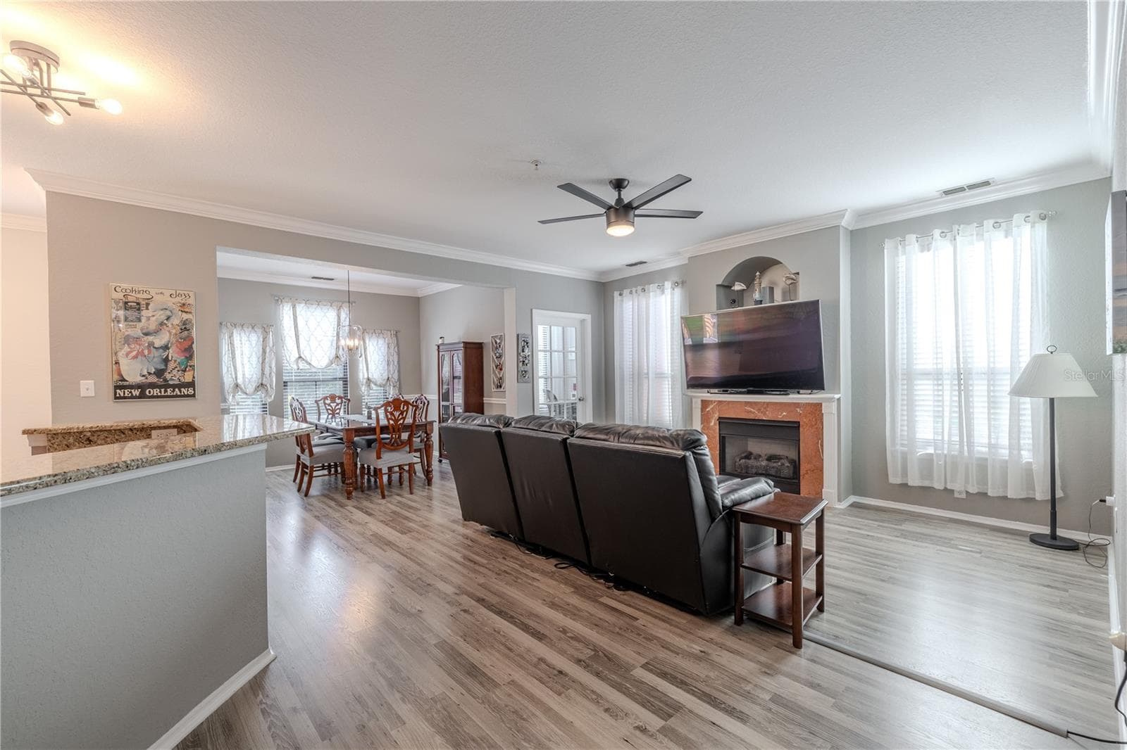 An expansive open-concept layout connects the living room, dining area, and kitchen, featuring crown molding, wide-plank flooring, modern lighting, and seamless flow ideal for everyday living and entertaining. - 2738 VIA TIVOLI #220B, CLEARWATER