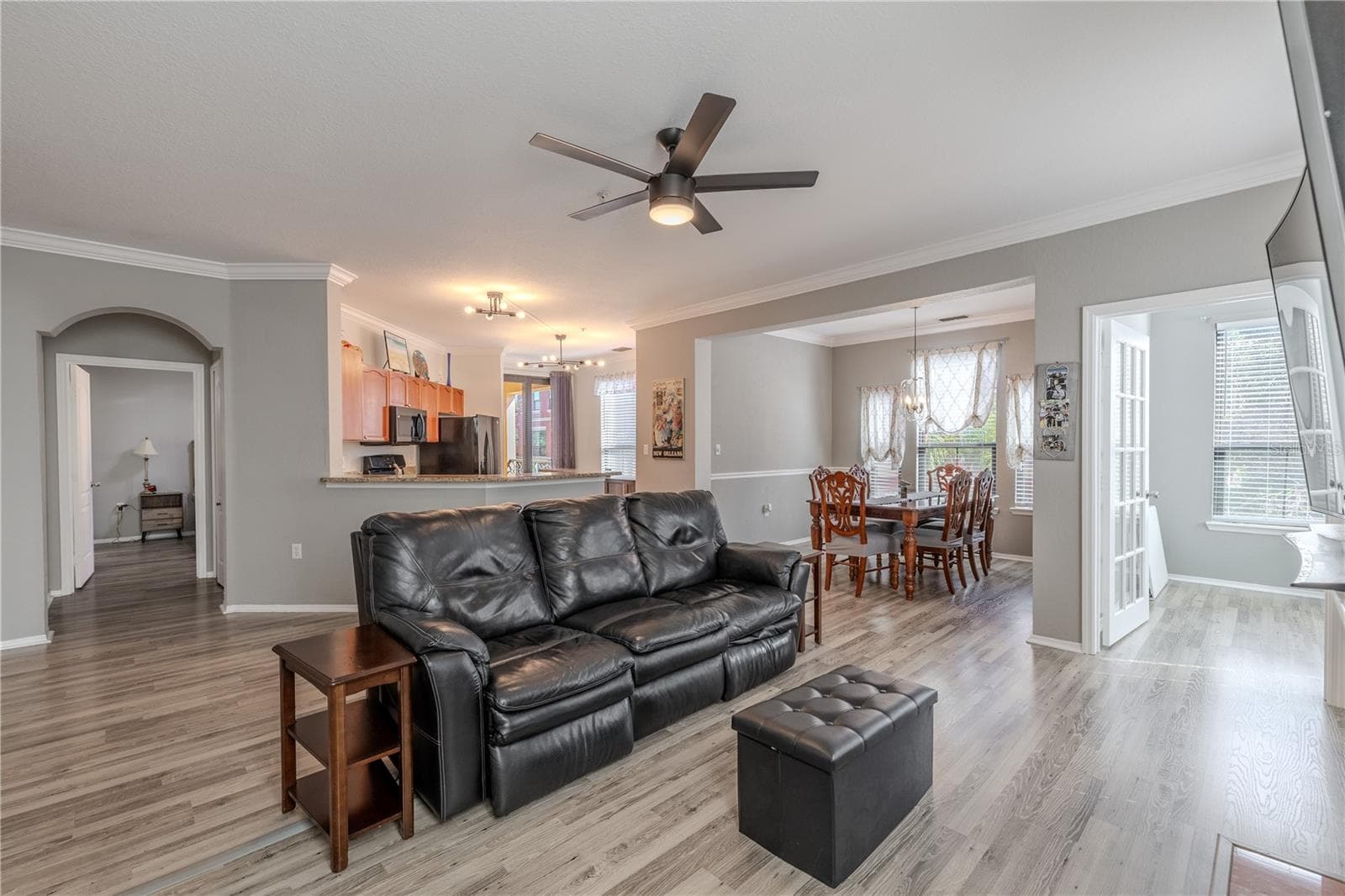 Spacious open-concept living area with updated vinyl wood-look flooring, crown molding, and a modern ceiling fan, flowing seamlessly into the dining space and kitchen for easy everyday living and entertaining. - 2738 VIA TIVOLI #220B, CLEARWATER