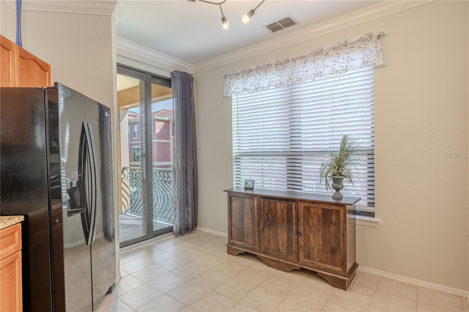 Natural light fills this eat-in kitchen area, featuring a large window, tile flooring, modern lighting, and sliding glass doors that open to the private balcony for easy indoor–outdoor living. - 2738 VIA TIVOLI #220B, CLEARWATER