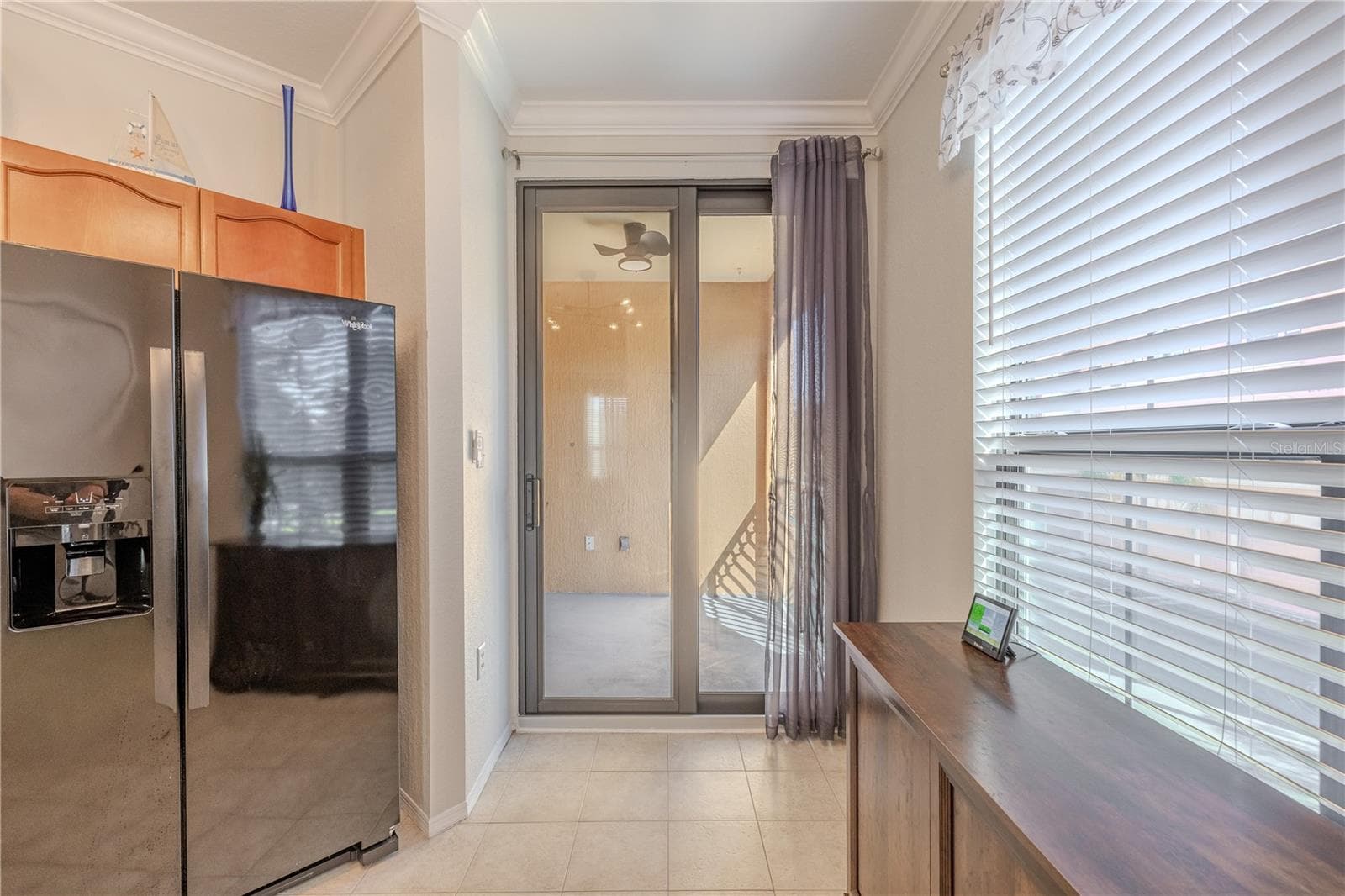 Another view of with natural light that fills this eat-in kitchen area, featuring a large window, tile flooring, modern lighting, and sliding glass doors that open to the private balcony for easy indoor–outdoor living. - 2738 VIA TIVOLI #220B, CLEARWATER
