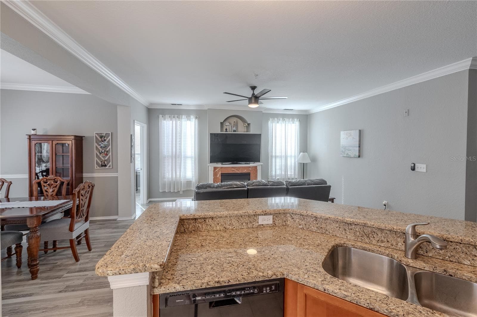This view highlights the spacious living area with modern ceiling fan, neutral tones, and seamless sight lines into the kitchen, emphasizing the open-concept layout ideal for everyday living and entertaining. - 2738 VIA TIVOLI #220B, CLEARWATER