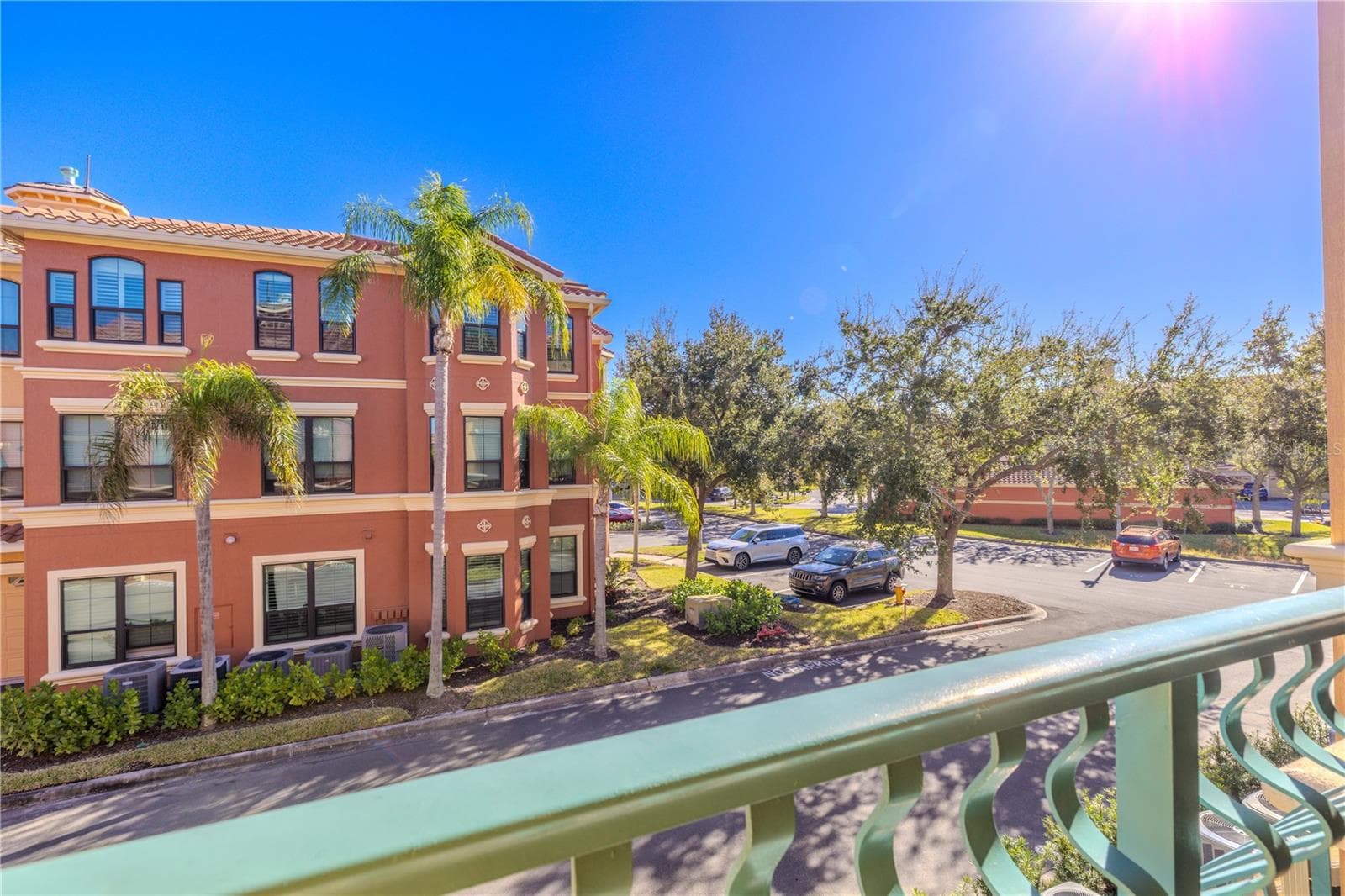 Sunny balcony view overlooking the beautifully maintained, palm-lined community with nearby parking and charming Mediterranean-style architecture. - 2738 VIA TIVOLI #220B, CLEARWATER
