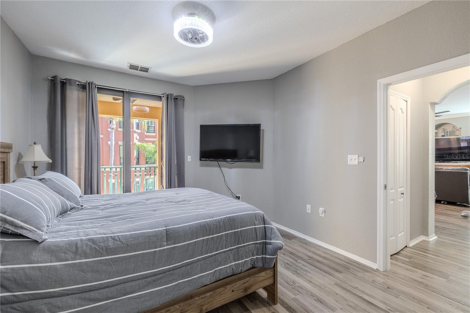 A en-suite bathroom view of the primary bedroom retreat featuring sliding glass doors to the private balcony, soft neutral tones, modern lighting, and easy access to the main living area, creating a bright and comfortable space to unwind. - 2738 VIA TIVOLI #220B, CLEARWATER