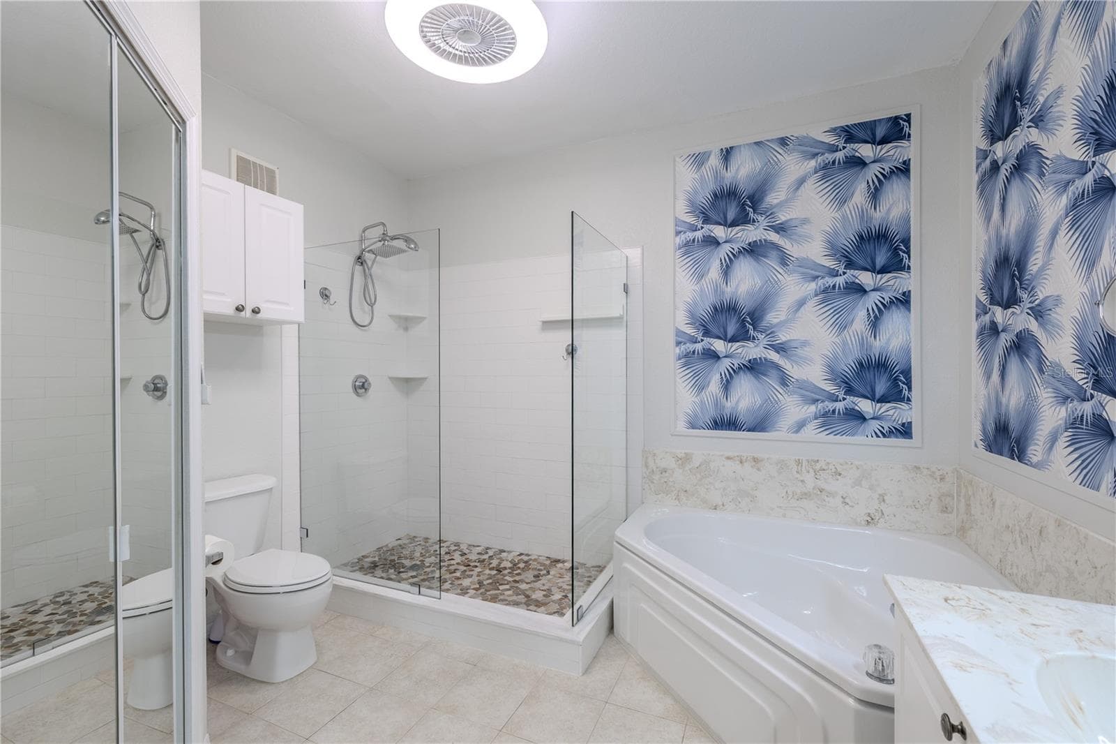 This angle showcases the seamless connection between the spa-style glass-enclosed shower and the spacious walk-in closet, highlighting exceptional storage, custom shelving, and a thoughtfully designed primary suite layout. - 2738 VIA TIVOLI #220B, CLEARWATER
