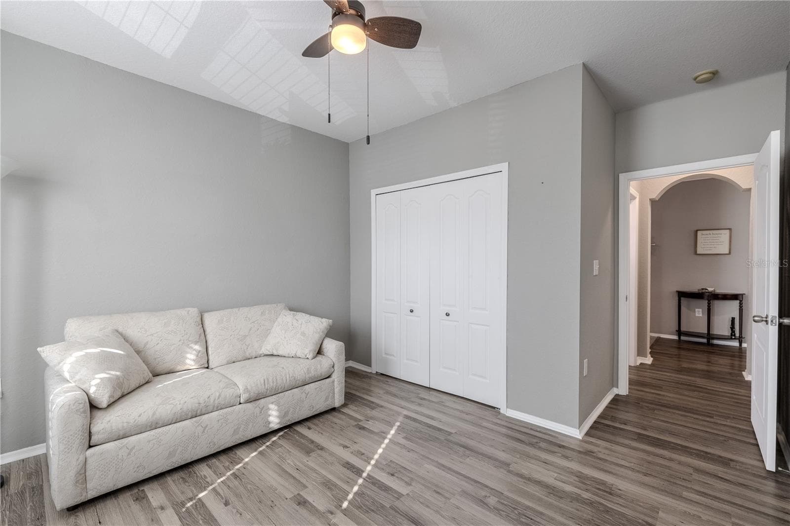 This view of the bright second bedroom features multiple windows for natural light, neutral finishes, wood-look laminate flooring, built in closet, and ample space to function comfortably as a guest room, home office, or flex space. - 2738 VIA TIVOLI #220B, CLEARWATER