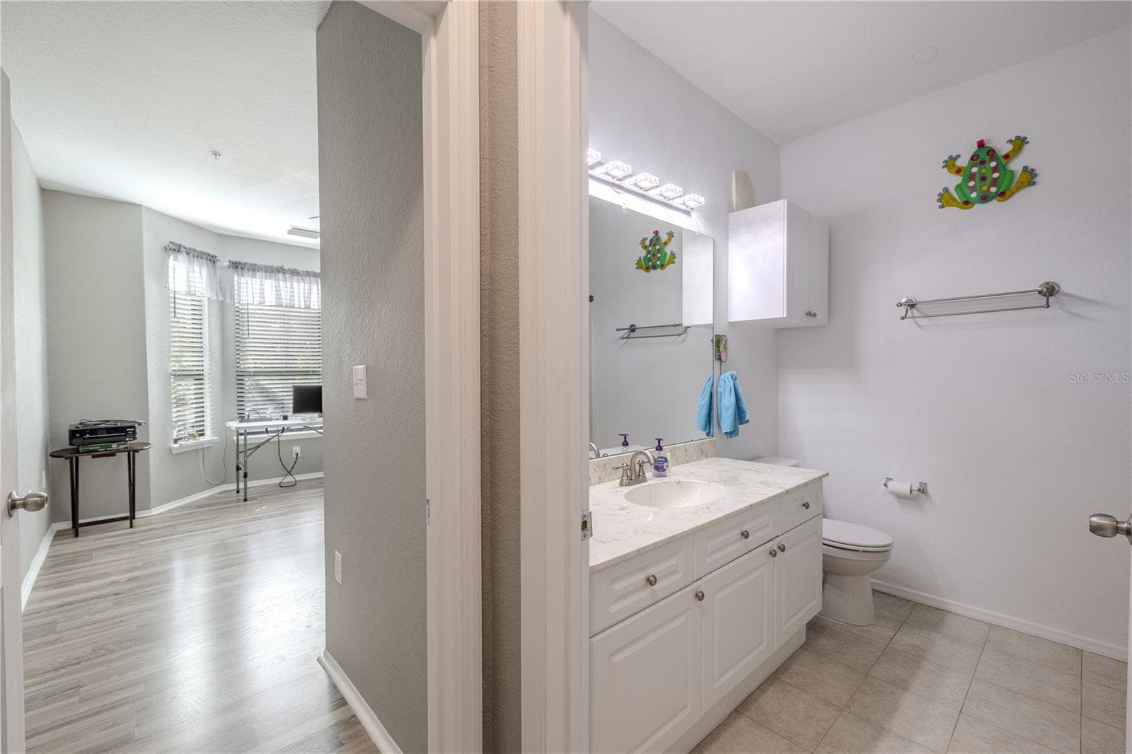 This second full bathroom offers a clean, bright design with a white vanity, solid-surface countertop, ample storage, and a convenient layout located just off the hallway and adjacent to the second bedroom. - 2738 VIA TIVOLI #220B, CLEARWATER