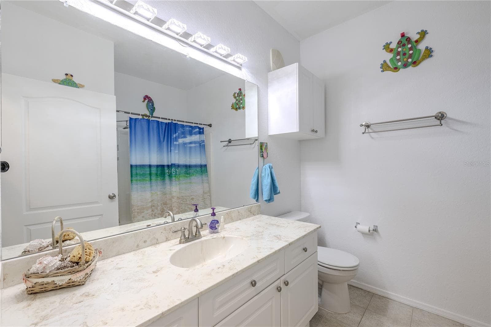 This bright second bathroom features a wide vanity with a solid-surface countertop, ample cabinetry, a full-size tub/shower combination, and cheerful natural light, making it ideal for guests or secondary bedrooms. - 2738 VIA TIVOLI #220B, CLEARWATER