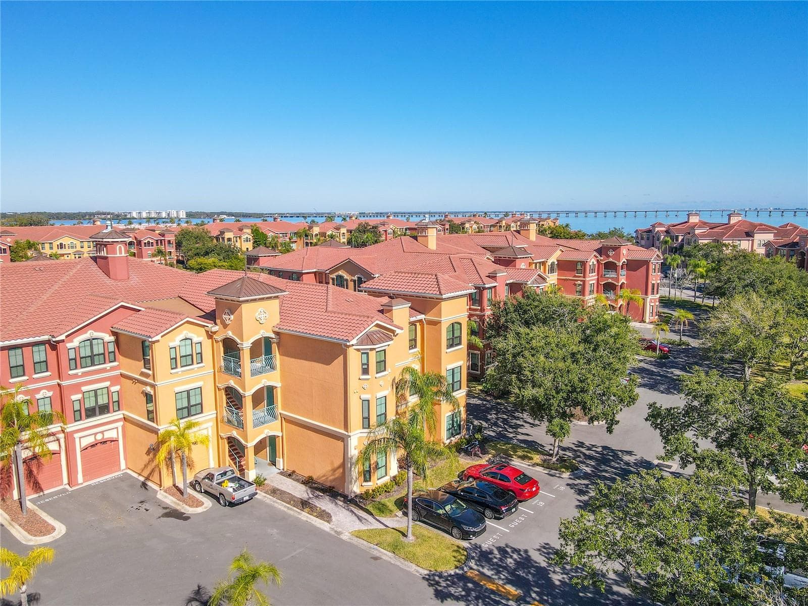 This aerial view highlights the sun-drenched Mediterranean elegance rising above palm-lined grounds, welcoming you to refined waterfront living at The Grand Bellagio. - 2738 VIA TIVOLI #220B, CLEARWATER