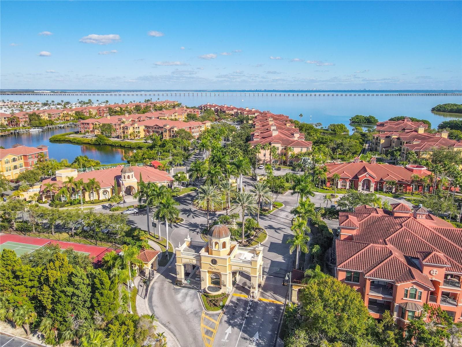 Sweeping aerial views showcase the vibrant Mediterranean-style community set against sparkling bay waters and an iconic bridge backdrop, capturing the essence of relaxed waterfront living. - 2738 VIA TIVOLI #220B, CLEARWATER