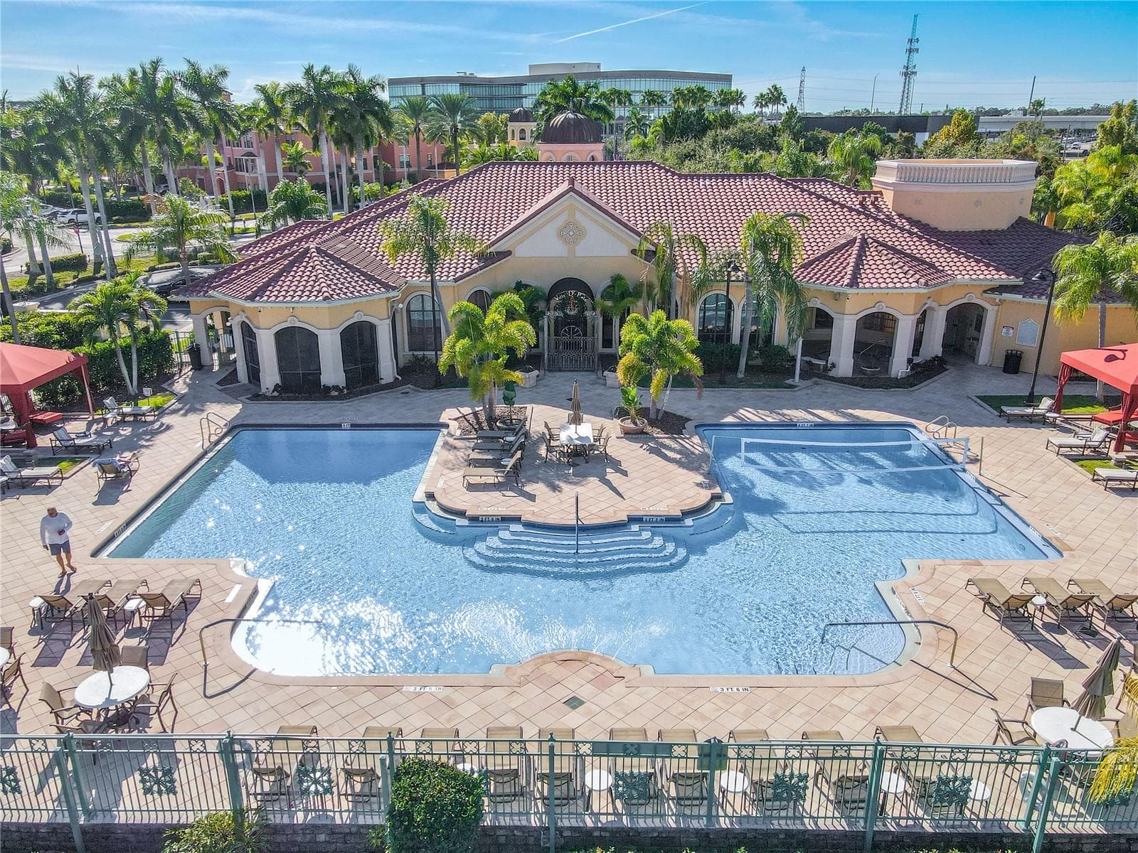 This aerial view further shows the resort-style heated clubhouse pool and spa with a spacious sundeck, lounge seating, and private rentable cabanas—perfect for relaxing, entertaining, and soaking up the Florida sunshine. - 2738 VIA TIVOLI #220B, CLEARWATER