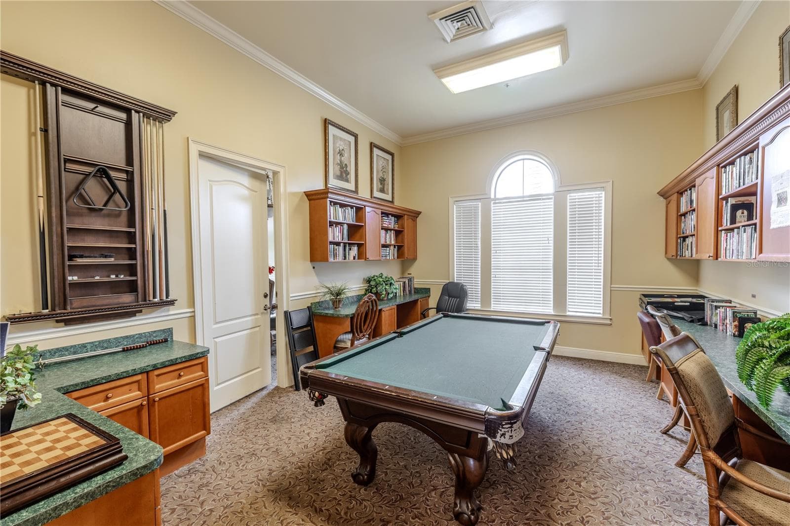 Clubhouse game and lounge room featuring a billiards table, built-in counters and cabinetry, and a bright arched window—perfect for socializing, playing pool, or relaxing with neighbors. - 2738 VIA TIVOLI #220B, CLEARWATER