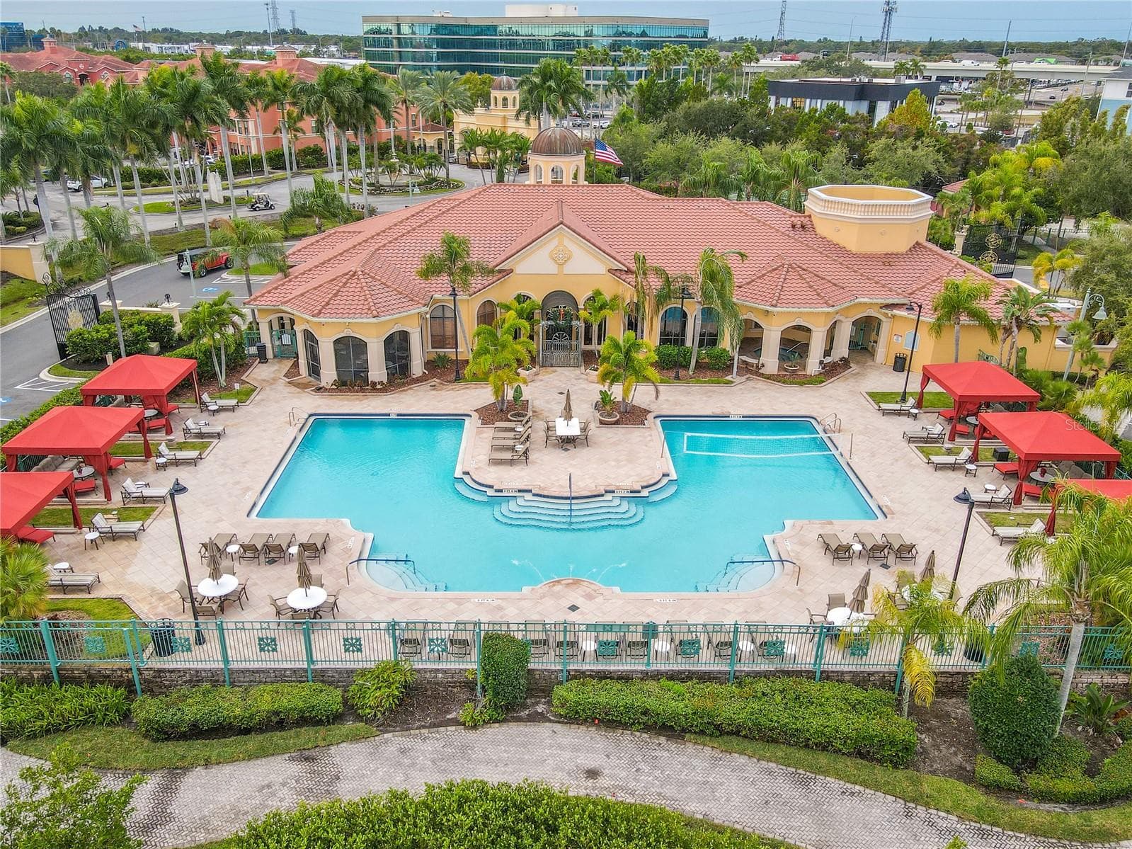 Front aerial resort-style heated clubhouse pool and spa with a spacious sundeck, lounge seating, and private rentable cabanas—perfect for relaxing, entertaining, and soaking up the Florida sunshine. - 2738 VIA TIVOLI #220B, CLEARWATER