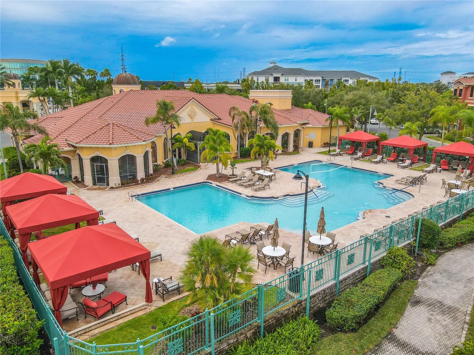Corner aerial resort-style heated clubhouse pool and spa with a spacious sundeck, lounge seating, and private rentable cabanas—perfect for relaxing, entertaining, and soaking up the Florida sunshine. - 2738 VIA TIVOLI #220B, CLEARWATER