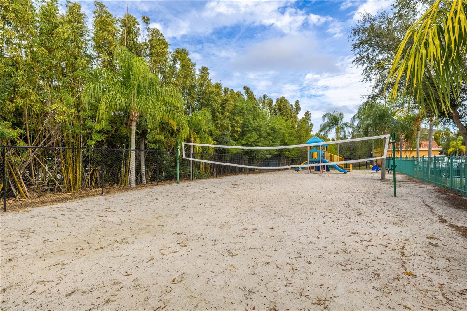 Community sand volleyball court and playground area, surrounded by lush tropical landscaping—perfect for outdoor fun and active living. - 2738 VIA TIVOLI #220B, CLEARWATER