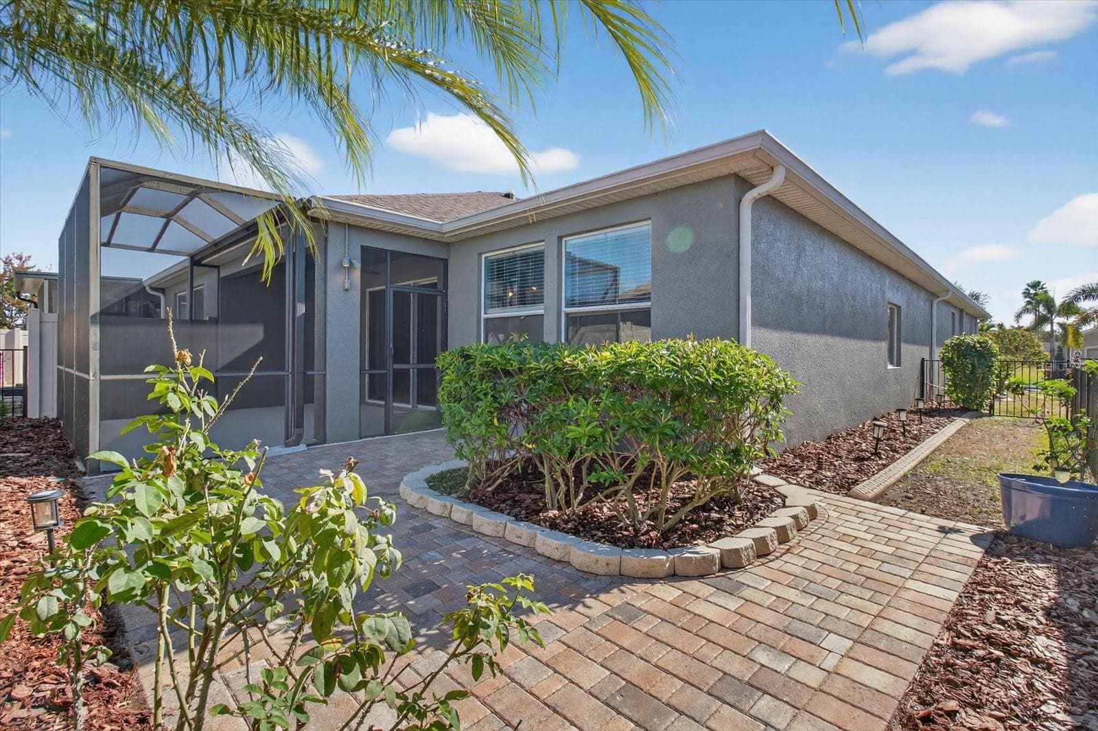 Rear exterior with tropical landscaping and an extended brick paver patio. - 2153 BARRACUDA CT, HOLIDAY