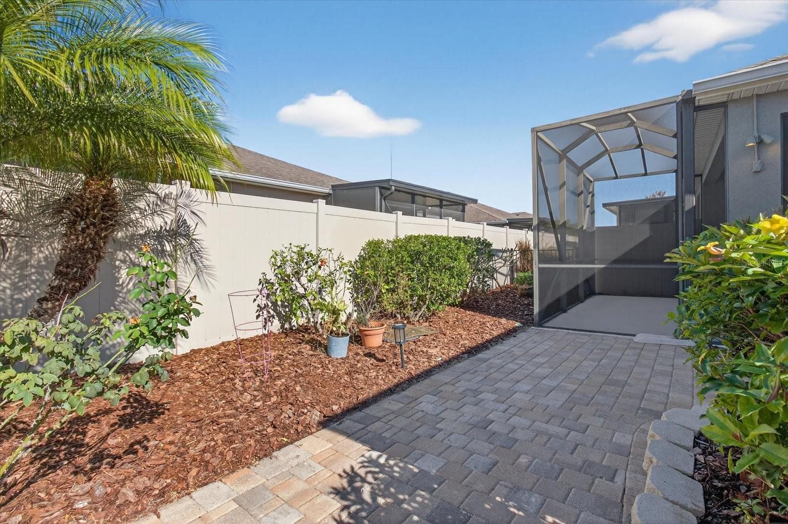 Fenced outdoor area with brick paver walkway and low-maintenance landscaping. - 2153 BARRACUDA CT, HOLIDAY
